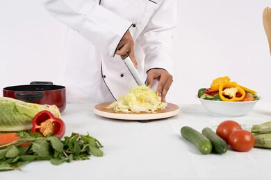 احترافية تقطيع الخضار، شغف التدرب على مهارة الطهي وإعداد الطعام، بورتريه مقرب لرجل عربي خليجي اماراتي يرتدي زي العمل يحضر طبق صحي مفيد، شيف سعودي يقوم بتحضير سلطة الخضراوات الطازجة، استخدام المكونات والمقادير المناسبة للوجبة، خلفية بيضاء