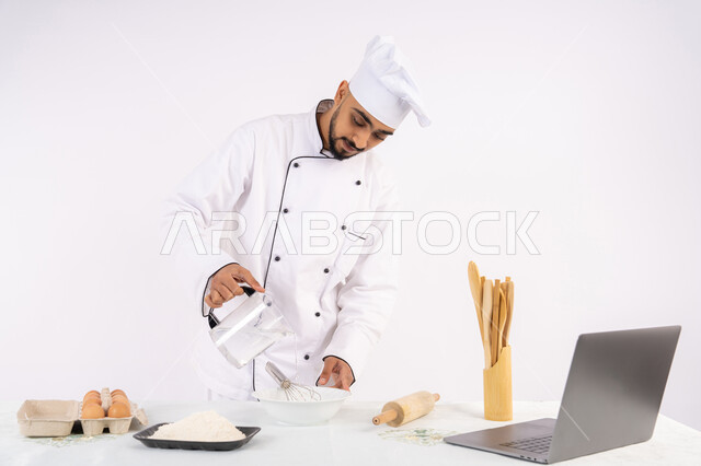 تصوير ومشاركة الوصفة عبر المواقع باستخدام الحاسوب المحمول، طاهي سعودي يقوم بتجهيز المكونات لصناعة الخبز والفطور، إعداد المخبوزات والمعجنات الشهية، بورتريه لرجل عربي خليجي اماراتي يرتدي زي العمل يقوم بخفق المكونات مع الدقيق الابيض لتحضير الطعام، خلفية بيضاء
