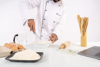 نشر الوصفة عبر المواقع باستخدام الحاسوب المحمول، طاهي سعودي يقوم بتجهيز المكونات لصناعة الخبز والفطور، إعداد المخبوزات والمعجنات الشهية، بورتريه لرجل عربي خليجي اماراتي يرتدي زي العمل يقوم بخفق المكونات مع الدقيق الابيض لتحضير الطعام، خلفية بيضاء