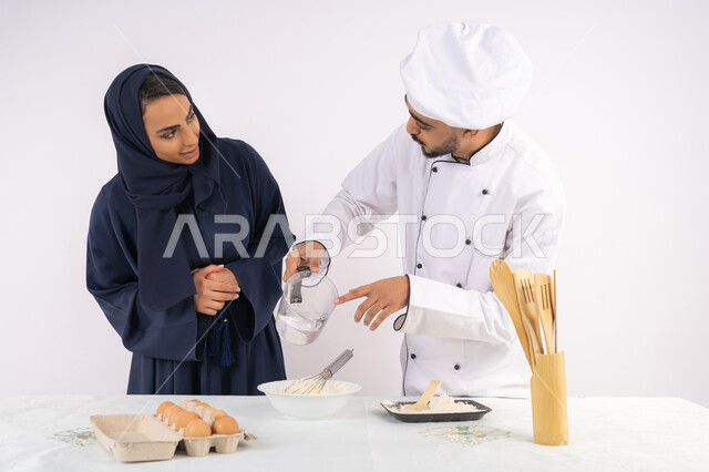 المقادير والمكونات المعيارية، ربة منزل سعودية تقوم بتعلم صناعة الخبز والمعجنات،  دورة تحضير وإعداد المخبوزات الشهية، بورتريه لشيف عربي خليجي اماراتي يقوم بتدريب إمرأة على اساسيات العمل في المطبخ، خلفية بيضاء