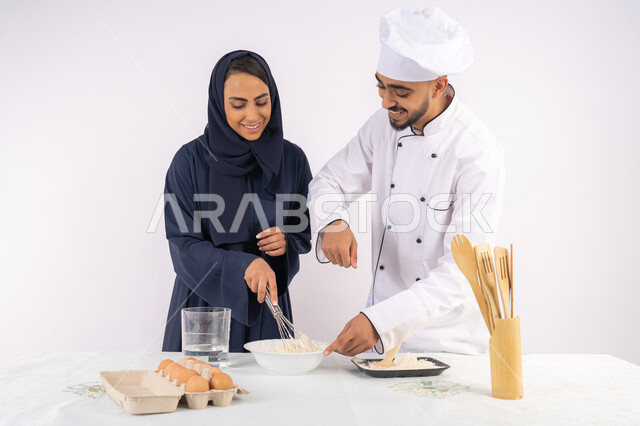 التدرب على المقادير والمكونات المعيارية، ربة منزل سعودية تقوم بتعلم صناعة الخبز والمعجنات،  دورة تحضير وإعداد المخبوزات الشهية، بورتريه لشيف عربي خليجي اماراتي يقوم بتدريب إمرأة على اساسيات العمل في المطبخ، خلفية بيضاء