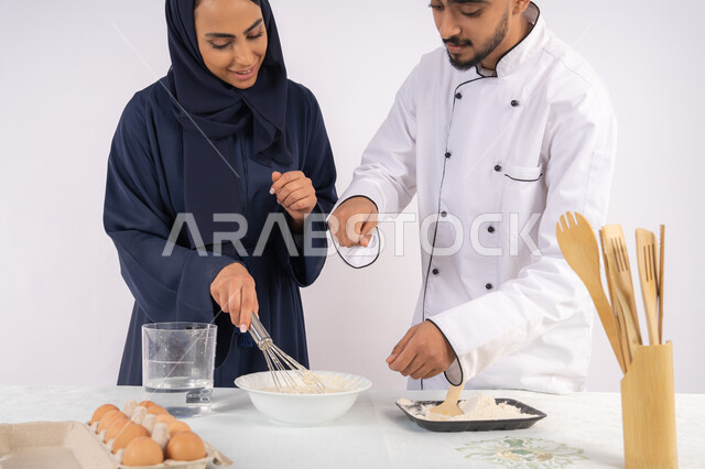 Setting standard quantities and ingredients, a Saudi housewife learning how to make bread and pastries, a course on preparing and making delicious baked goods, a portrait of an Arab Gulf Emirati chef training a woman on the basics of working in the kitchen, white background