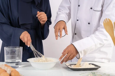 المقادير والمكونات المعيارية، ربة منزل سعودية تقوم بتعلم صناعة الخبز والمعجنات،  دورة تحضير وإعداد المخبوزات الشهية، بورتريه لشيف عربي خليجي اماراتي يقوم بتدريب إمرأة على اساسيات العمل في المطبخ، خلفية بيضاء