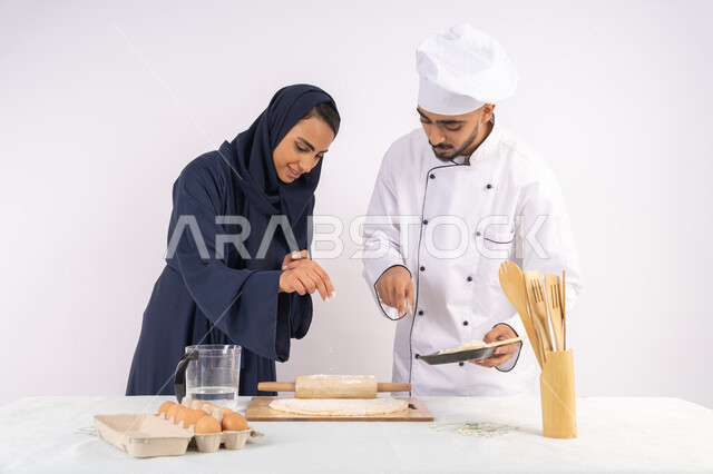 مهارة فرد العجين باستخدام الشوبك (النشابة)، ربة منزل سعودية تقوم بتعلم صناعة الخبز والمعجنات،  دورة تحضير وإعداد المخبوزات الشهية، بورتريه لشيف عربي خليجي اماراتي يقوم بتدريب إمرأة على اساسيات العمل في المطبخ، خلفية بيضاء