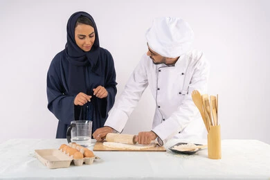 ربة منزل سعودية تقوم بتعلم صناعة الخبز والمعجنات، دورة تحضير وإعداد المخبوزات الشهية، بورتريه لشيف عربي خليجي اماراتي يقوم بتدريب إمرأة على اساسيات العمل في المطبخ، مهارة فرد العجين باستخدام الشوبك (النشابة)، خلفية بيضاء ربة منزل سعودية تقوم بتعلم صناعة الخبز والمعجنات، دورة تحضير وإعداد المخبوزات الشهية، بورتريه لشيف عربي خليجي اماراتي يقوم بتدريب إمرأة على اساسيات العمل في المطبخ، مهارة فرد العجين باستخدام الشوبك (النشابة)، خلفية بيضاء