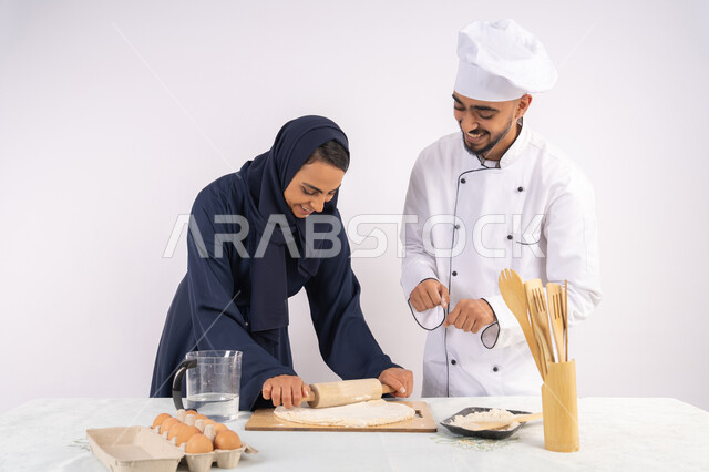 مهارة فرد العجين باستخدام الشوبك (النشابة)، ربة منزل سعودية تقوم بتعلم صناعة الخبز والمعجنات،  دورة تحضير وإعداد المخبوزات الشهية، بورتريه لشيف عربي خليجي اماراتي يقوم بتدريب إمرأة على اساسيات العمل في المطبخ، خلفية بيضاء