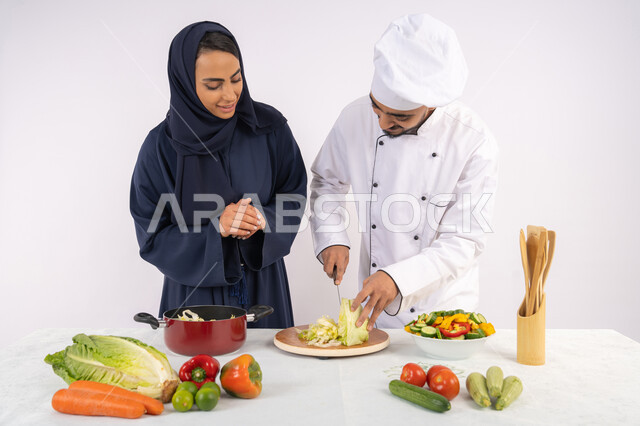 Professional vegetable cutting, Saudi housewife learning to cook and prepare dishes, course on preparing recipes for salads and delicious healthy meals, portrait of an Arab Gulf Emirati chef training a woman on the basics of working in the kitchen,white background