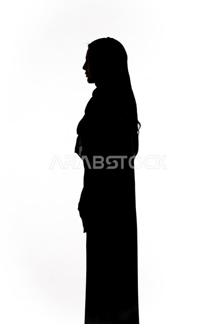 مفهوم الأناقة والاهتمام بالمظهر الخارجي، أزياء محجبات عصرية راقية، صورة ظلية لامرأة عربية خليجية إماراتية تقف باستقامه وايدي متقاطعه ،خلفية بيضاء