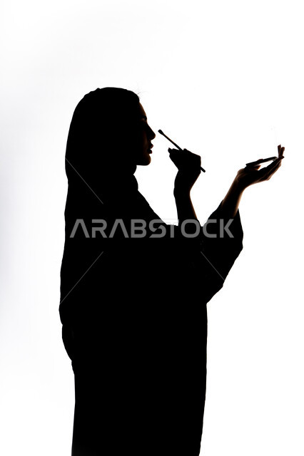 مفهوم الانوثه والنعومه، صورة ظلية لمرأة عربية خليجية اماراتيه، أدوات مكياج تتوريال ، الإهتمام بالجمال والمظهر الخارجي ، إستخدام إحدى أدوات التجميل ( فرشاة ظل العيون ) ، التسويق لمنتجات التجميل ، خلفية بيضاء