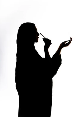 The concept of femininity and softness, a silhouette of an Arab Gulf Emirati woman, makeup tools tutorial, interest in beauty and external appearance, use of a cosmetic tool (eye shadow brush), marketing for cosmetic products, white background