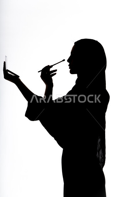 إستخدام إحدى أدوات التجميل ( فرشاة ظل العيون ) ، التسويق لمنتجات التجميل ،  صورة ظلية لمرأة عربية خليجية اماراتيه، الإهتمام بالجمال والمظهر الخارجي ، أدوات مكياج تتوريال ، خلفية بيضاء