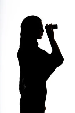 حب الاستكشاف والمغامرة,  صورة ظلية لمراه عربية خليجية اماراتية تحمل بيدها منظار ثنائي العينين و تنظر الى شيء ما، ايماءات السرور والاستمتاع، رؤية الاشياء البعيدة و تقريبها, الاشاره الى شئ بعيد،  خلفية بيضاء