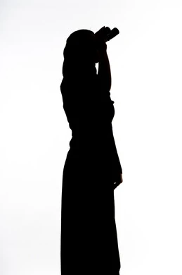 صورة ظلية لمراه عربية خليجية اماراتية تحمل بيدها منظار ثنائي العينين و تنظر الى شيء ما، ايماءات السرور والاستمتاع، رؤية الاشياء البعيدة و تقريبها, حب الاستكشاف و المغامرة, الاشاره الى شئ بعيد،  خلفية بيضاء