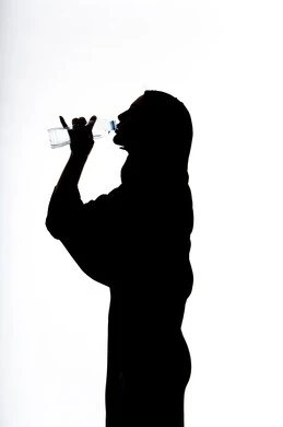 The importance of drinking pure water to maintain a fresh complexion, a silhouette of an Arab Gulf Emirati woman drinking water from a plastic bottle, eliminating toxins from the body, maintaining a healthy immune system, white background