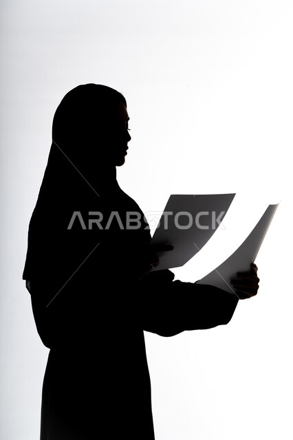 التعليم والثقافة ، متابعة الخطط والمشاريع ،قراءة الملاحظات والمعلومات ،صورة ظلية لمرأة عربية خليجية اماراتيه، بيدها أوراق خاصة بالعمل ، الأبحاث والتقارير ، خلفية بيضاء