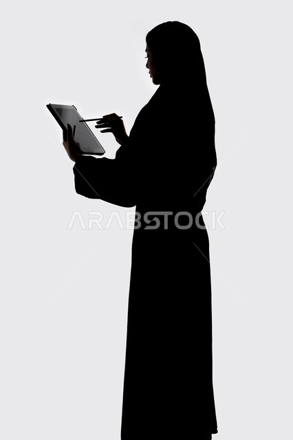 انجاز مهام العمل عن بعد ،  وسائل التواصل الإجتماعي ،دمج التكنولوجيا الحديثه فى الحياه اليوميه ، اجراء بث مباشر ،إستخدام اجهزة تقنية حديثة ،التقاط صور سيلفي تذكاريه بإستخدام التابلت ، اجراء مكالمه هاتفيه ،صورة ظلية لمرأة عربية خليجية اماراتيه ، خلفية بيضاء