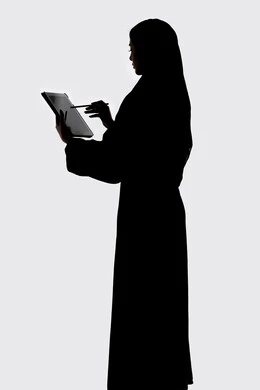 انجاز مهام العمل عن بعد ،  وسائل التواصل الإجتماعي ،دمج التكنولوجيا الحديثه فى الحياه اليوميه ، اجراء بث مباشر ،إستخدام اجهزة تقنية حديثة ،التقاط صور سيلفي تذكاريه بإستخدام التابلت ، اجراء مكالمه هاتفيه ،صورة ظلية لمرأة عربية خليجية اماراتيه ، خلفية بيضاء