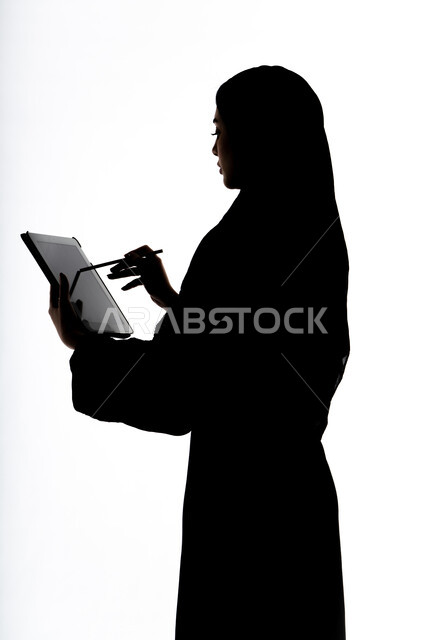 Social media, completing work tasks remotely, integrating modern technology into daily life, conducting a live broadcast, using modern technical devices, taking souvenir selfies using a tablet, making a phone call, silhouette of an Arab Gulf Emirati woman, white background