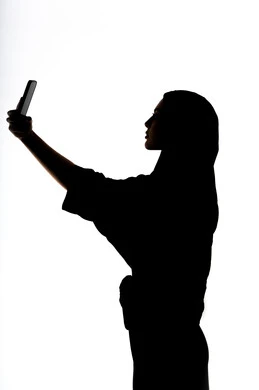 إستخدام اجهزة تقنية حديثة ، التواصل الإجتماعي ،اجراء مكالمه هاتفيه ،التقاط صور سيلفي تذكاريه بإستخدام الهاتف المحمول ، صورة ظلية لمرأة عربية خليجية اماراتيه ، بث مباشر ، خلفية بيضاء