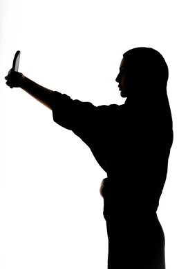 التقاط صور سيلفي تذكاريه بإستخدام الهاتف المحمول ، اجراء مكالمه هاتفيه ،صورة ظلية لمرأة عربية خليجية اماراتيه ، إستخدام اجهزة تقنية حديثة ، التواصل الإجتماعي ، بث مباشر ، خلفية بيضاء