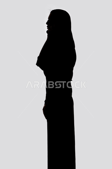 Communicating with family and friends, taking souvenir selfies using a mobile phone, using modern technology, conducting a live broadcast, making a phone call, silhouette of an Arab Gulf Emirati woman, social media, white background
