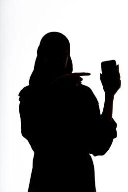 الاشاره الى شاشه الجوال، التواصل مع الاهل والاصدقاء، التقاط صور سيلفي تذكاريه ،إستخدام اجهزة تقنية حديثة ، اجراء بث مباشر ،  اجراء مكالمه هاتفيه ،صورة ظلية لمرأة عربية خليجية اماراتيه ،وسائل التواصل الإجتماعي ، خلفية بيضاء