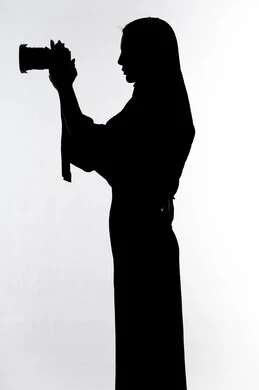 كاميرا عالية الدقة ،إحتراف التصوير ،هواية التصوير ، إلتقاط الصور التذكارية ، صورة ظلية لامراه عربيه خليجيه اماراتيه ، تحمل بيده كاميرا تصوير عالية الدقة ، مصوره اماراتي ، خلفية بيضاء