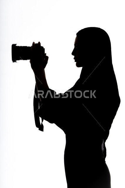 إحتراف التصوير ،هواية التصوير ، إلتقاط الصور التذكارية ، كاميرا عالية الدقة ،صورة ظلية لامراه عربيه خليجيه اماراتيه ، تحمل بيده كاميرا تصوير عالية الدقة ، مصوره اماراتي ، خلفية بيضاء