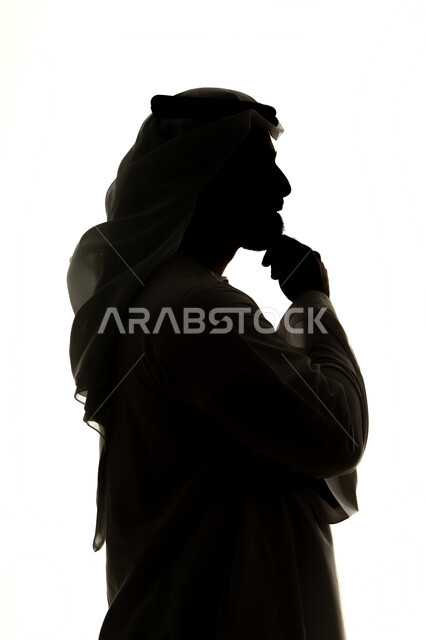 تعابير شرود الذهن والتمعن، التأمل والتخطيط للمستقبل، ايجاد حل لمشكلة ما،  صورة ظلية لرجل عربي خليجي اماراتي يضع يده على ذقنه ينظر الى مكان ما بايماءات التفكير والتركيز،  خلفية بيضاء