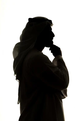 تعابير شرود الذهن والتمعن، التأمل والتخطيط للمستقبل، ايجاد حل لمشكلة ما،  صورة ظلية لرجل عربي خليجي اماراتي يضع يده على ذقنه ينظر الى مكان ما بايماءات التفكير والتركيز،  خلفية بيضاء