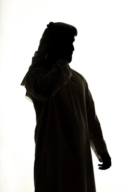 Online chat, integration of modern technologies into daily life, accomplishing tasks remotely, social networking, making a video call using a mobile phone, communication and chatting, silhouette of an Arab Gulf Emirati man, white background