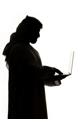 E-marketing, professions and jobs, integration of modern technologies into daily life, surfing the internet, using technology devices, silhouette of an Arab Gulf Emirati man, using a laptop, working remotely, white background