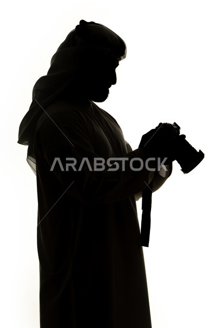 إلتقاط الصور التذكارية ،  هواية التصوير ،كاميرا عالية الدقة ،صورة ظلية لرجل عربي خليجي اماراتي ، يحمل بيده كاميرا تصوير عالية الدقة ،مصوره اماراتي ، إحتراف التصوير ، خلفية بيضاء