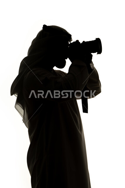 هواية التصوير ،كاميرا عالية الدقة ،صورة ظلية لرجل عربي خليجي اماراتي ، يحمل بيده كاميرا تصوير عالية الدقة ، إلتقاط الصور التذكارية ، مصوره اماراتي ، إحتراف التصوير ، خلفية بيضاء
