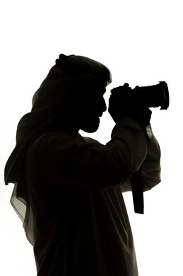 كاميرا عالية الدقة ، هواية التصوير ،صورة ظلية لرجل عربي خليجي اماراتي ، يحمل بيده كاميرا تصوير عالية الدقة ، إلتقاط الصور التذكارية ، مصوره اماراتي ، إحتراف التصوير ، خلفية بيضاء