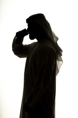 الاستمتاع بالمشروبات ساخنة ، صورة ظلية لرجل عربي خليجي اماراتي يحمل الفنجان ، احتساء المشروبات والأعشاب الشتوية الدافئة، تعديل المزاج بتناول الكافيين، خلفية بيضاء