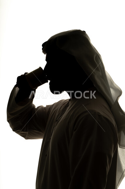 صورة ظلية لرجل عربي خليجي اماراتي يحمل الفنجان ، مشروبات ساخنة ، احتساء المشروبات الساخنة والأعشاب الشتوية الدافئة، تعديل المزاج بتناول الكافيين، خلفية بيضاء