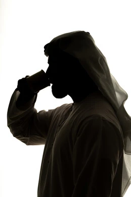 Silhouette of an Arab Gulf Emirati man holding a cup, hot drinks, sipping hot drinks and warm winter herbs, mood boosting caffeine intake, white background