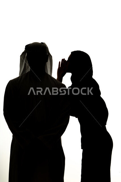 ايماءات الانصات والتركيز بالكلام، النميمة والتحدث عن شخص ما، التحدث بصوت منخفض، صورة ظلية لامراه عربيه خليجيه اماراتيه تهمس بإذن زوجها، مفهوم الكتمان وحفظ الأسرار بين الشقيقات، خلفية بيضاء