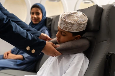 ايماءات النعاس والتعب والإرهاق, مفهوم السياحة و السفر, التنقل باستخدام وسائل النقل الجوية, الضيافة و حسن الاستقبال , طفل عربي خليجي عماني يرتدي الدشداشة و الكمه ينام على المقعد داخل الطائرة بجانب والدته
