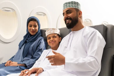 عطلة صيفية سعيدة, رحلة سياحية عائلية، قضاء وقت ممتع داخل الطائرة , عائله عربيه خليجيه عمانية ترتدي الزي التقليدي تجلس على المقعد داخل الطائرة فى رحله جويه , ايماءات السعاده و السرور, خطوط الطيران العماني