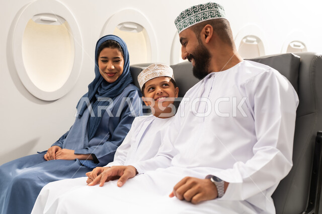 رحلة سياحية عائلية، قضاء وقت ممتع داخل الطائرة , عائله عربيه خليجيه عمانية ترتدي الزي التقليدي تجلس على المقعد داخل الطائرة فى رحله جويه , ايماءات السعاده و السرور, خطوط الطيران العماني