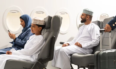 السفر بين المدن والدول, عائلة عربيه خليجيه عمانية ترتدي الزي التقليدي تجلس داخل الطائرة بايماءات السعاده و السرور , امراة عربيه خليجيه تمسك الهاتف المحمول , تصفح مواقع التواصل الالكتروني