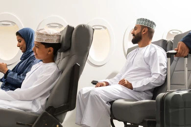 التنقل عبر الخطوط الجوية, عائلة عربيه خليجيه عمانية ترتدي الزي التقليدي تجلس داخل الطائرة بايماءات السعاده و السرور , امراة عربيه خليجيه تمسك الهاتف المحمول , تصفح مواقع التواصل الالكتروني
