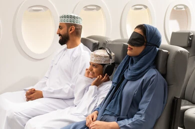 السفر مع العائلة, خطوط الطيران الجوي, عائلة عربية خليجية عمانية ترتدي الزي التقليدي تجلس داخل الطائرة ، حسن الضيافة ، سياحة وسفر ، امراة خليجيه ترتدي الماسك الاسود على عينها تنام على مقعدها , ايماءات السعادة و السرور