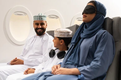 خطوط الطيران الجوي, عائلة عربية خليجية عمانية ترتدي الزي التقليدي  تجلس داخل الطائرة  ، حسن الضيافة  ، سياحة وسفر ، رحلة سياحية ، امراة خليجيه ترتدي الماسك الاسود على عينها تنام على مقعدها , ايماءات السعادة و السرور