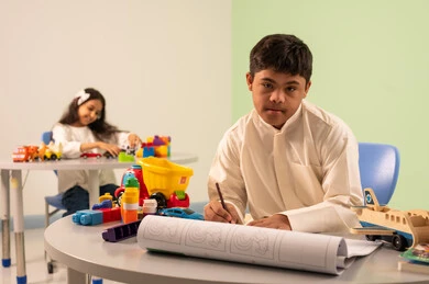 مفهوم الاهتمام بالهوايات،قضاء اوقات ممتعه ، ولد عماني مصاب بمتلازمه داون يقوم بالرسم والتلوين ، تنمية المهارات الفنيه في الروضات السعودية  ،بنت عربيه سعوديه ترتدي الزي الكاجوال تجلس على كرسي متحرك، تلعب بالالعاب البلاستيكيه الملونه