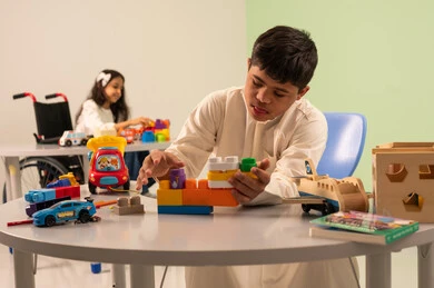 تعزيز النشاط الذهني في الروضات السعودية ، نشاطات ترفيهية لذوي الاحتياجات الخاصة ، اهتمام المجتمع السعودي بأصحاب الهمم,قضاء اوقات ممتعه ،تشجيع ورعاية وتطوير مهارات الأطفال، ولد عربي سعودي مصاب بمتلازمه داون يقوم بتركيب المكعبات بتعابير السعاده