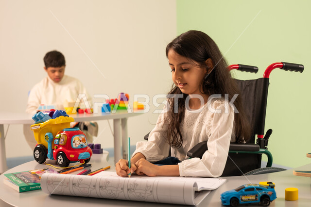 ولد سعودي مصاب بمتلازمه داون يقوم باللعب بالمكعبات ، تنمية المهارات الفنيه في الروضات السعودية،تعابير التركيز والاستمتاع ،مفهوم الاهتمام بالهوايات،  قضاء اوقات ممتعه ، بنت عربيه عمانيه ترتدي الزي الكاجوال تقوم بالرسم والتلوين