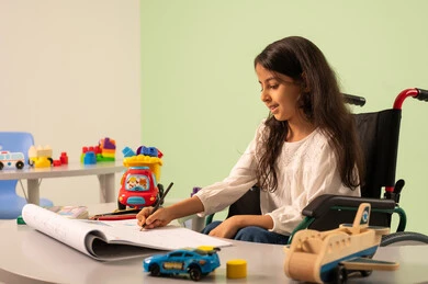 Having fun, developing artistic skills in Saudi kindergartens, the concept of interest in hobbies, a Saudi Arabian girl wearing casual clothes sitting in a wheelchair, drawing and coloring with expressions of concentration and enjoyment